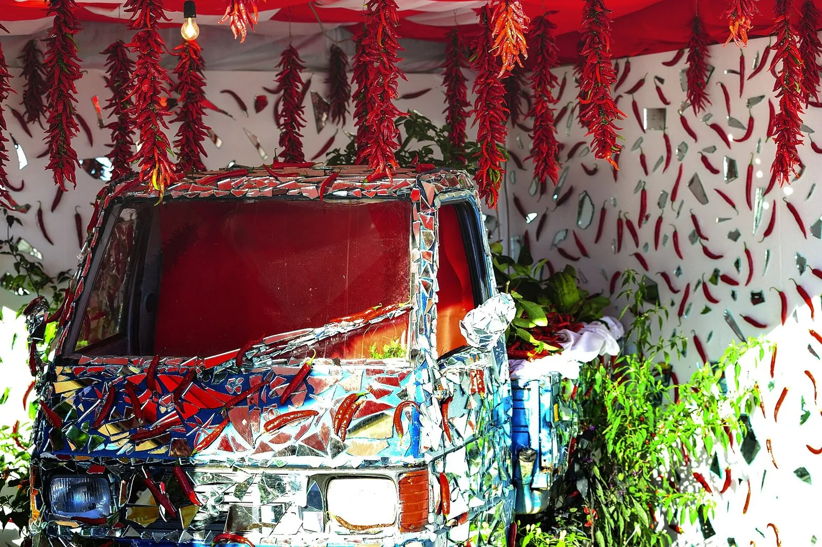 Allestimento con trecce di peperoncini rossi e un'Ape decorata a specchi durante il Peperoncino Festival di Diamante