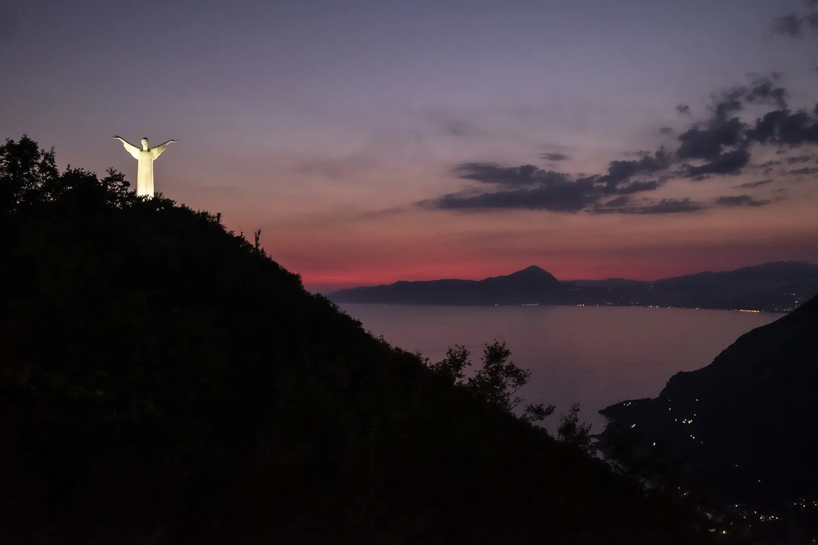 La statua del Cristo Redentore illuminata sul Monte San Biagio a Maratea, al tramonto sul golfo